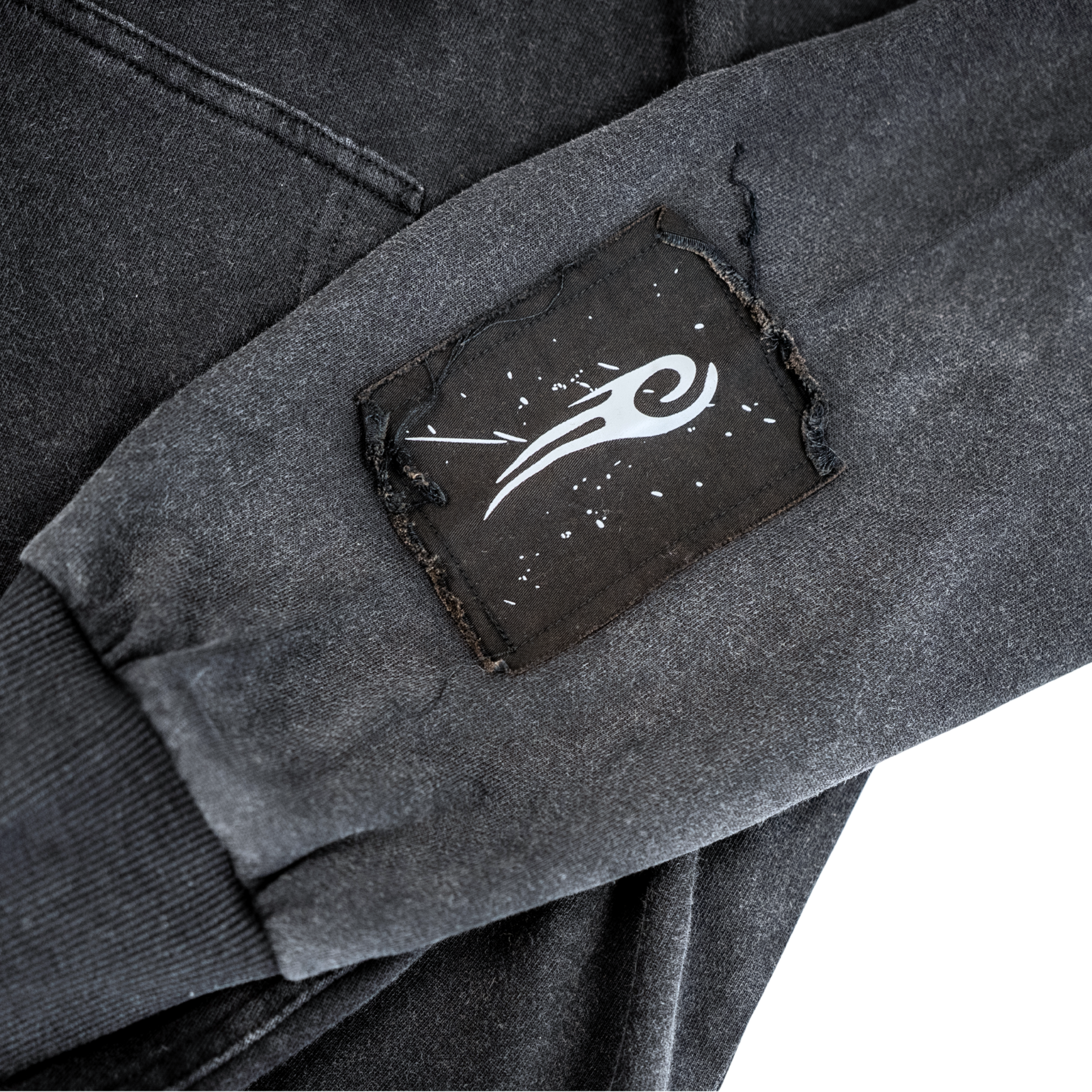 Black patch with the Tyson Hook on the left sleeve by the wrist.