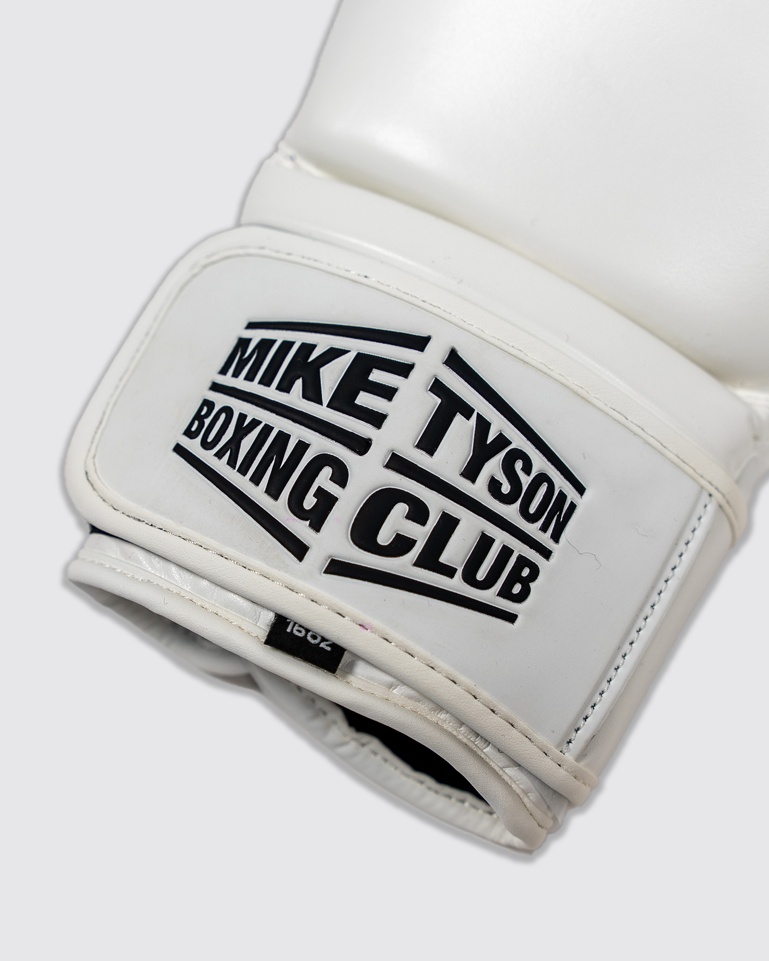 Close up of the black Mike Tyson Boxing Club logo on the wrist of the white glove.