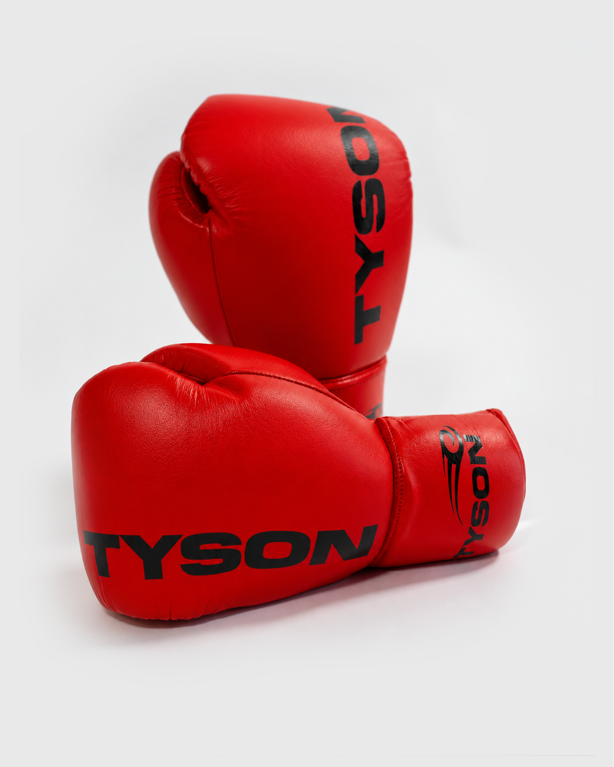 Red boxing gloves. Black text saying "Tyson" runs vertically towards the fingers on the back of the gloves, while the Tyson Pro logo is on the wrist. The palm side of the glove features laces.