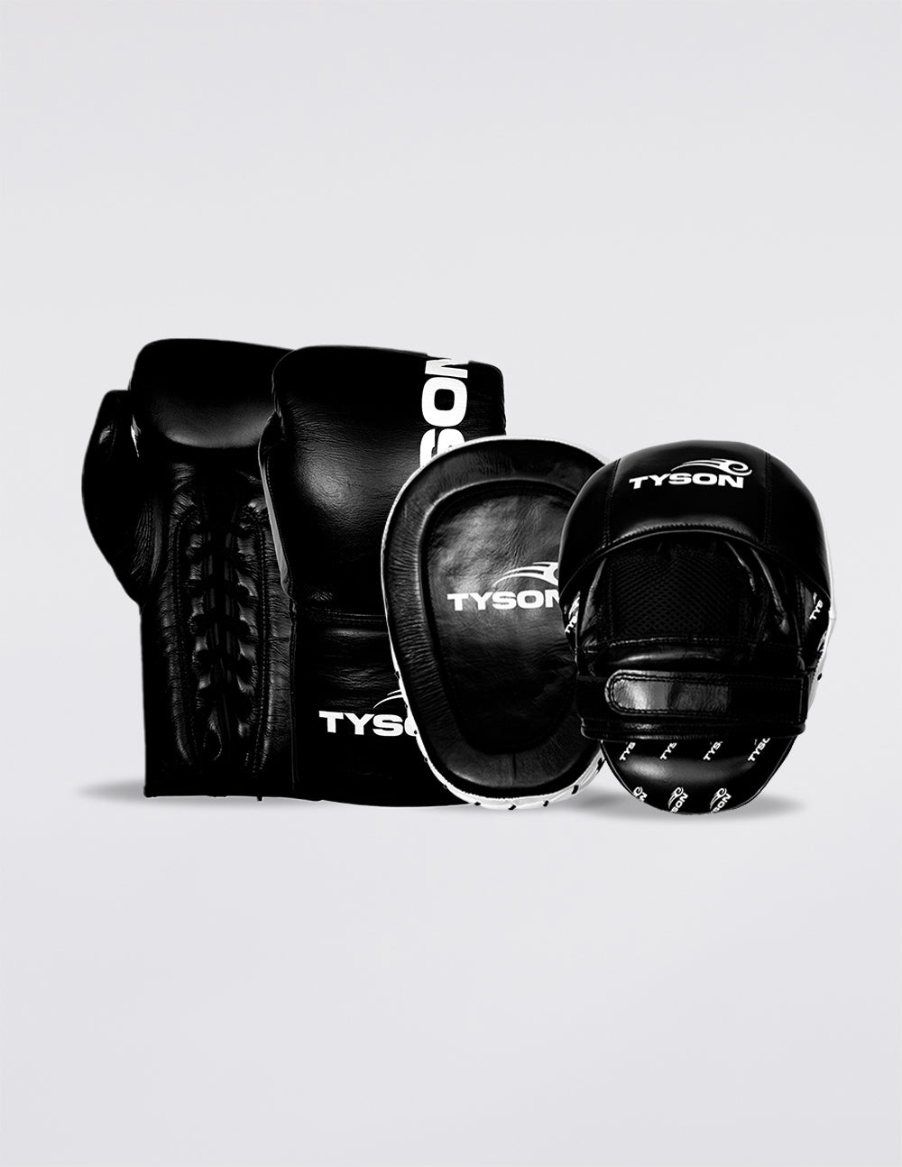 Black boxing gloves. White text saying "Tyson" runs vertically towards the fingers on the back of the gloves, while the Tyson Pro logo is on the wrist. The palm side of the glove features laces.
Black focus mitts with a white border. A white Tyson Pro logo is featured on the face of the mitt. The logo is also featured on the top of the backside, and a pattern with the logos is at the bottom. There is mesh on the backside along with the tightening strap.