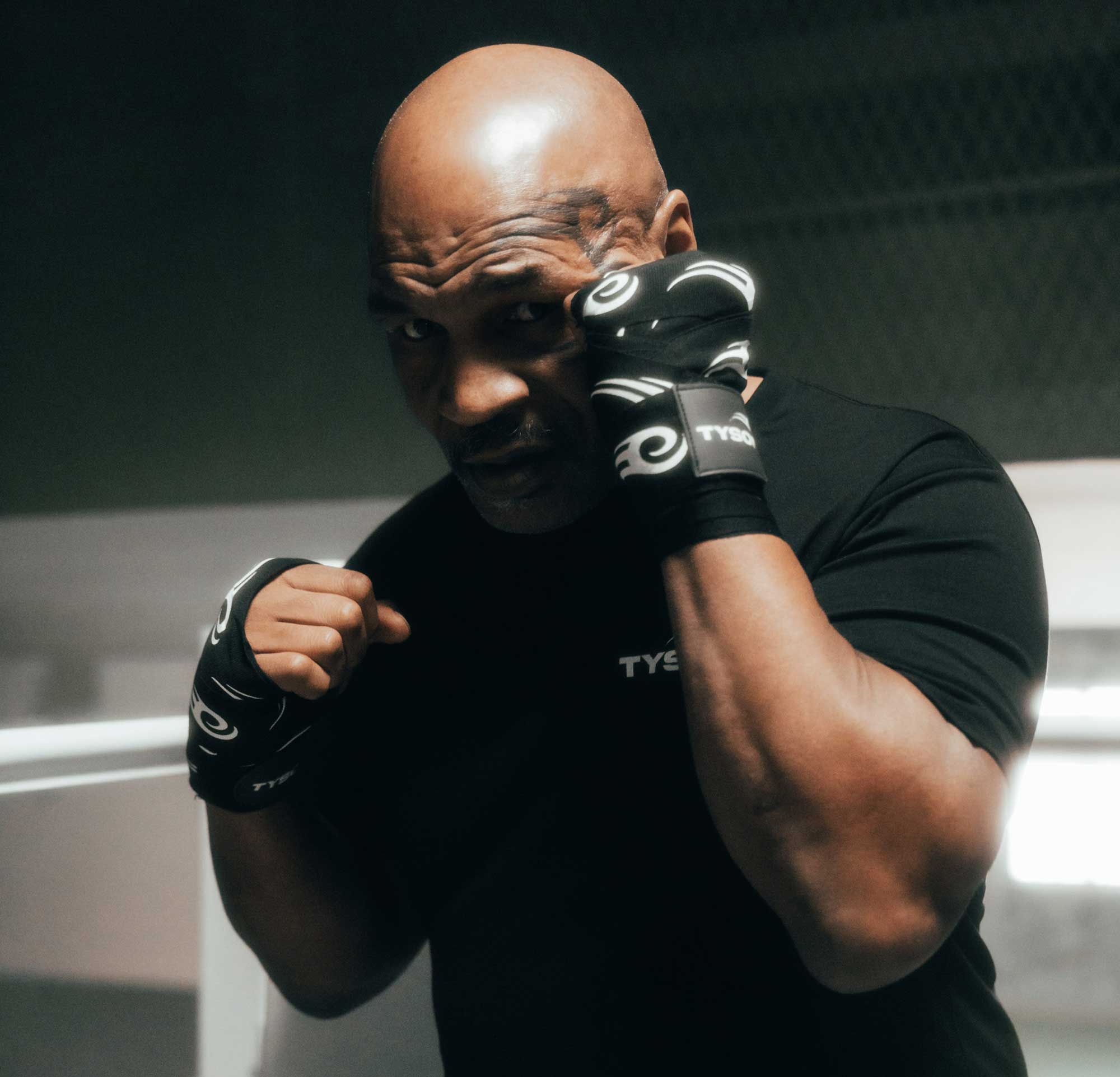 Black hand wraps with the Tyson Pro logo in white on the strap, and the Tyson half tribal logo repeatedly running along the entire wrap.