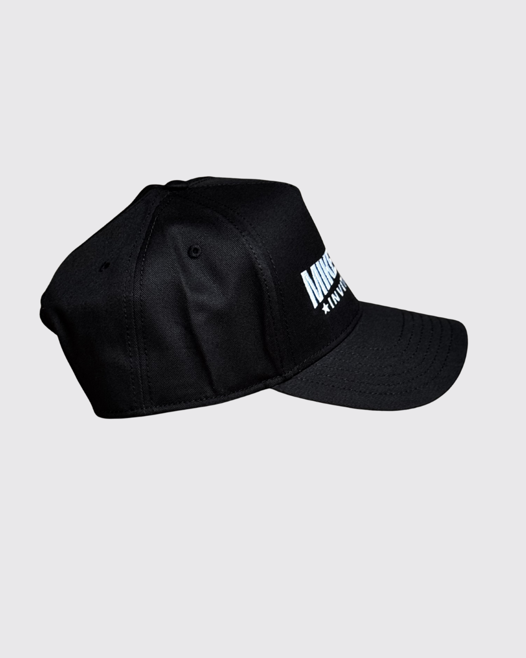 A black hat with the Mike Tyson Invitational Logo on the front panel, shown from the side