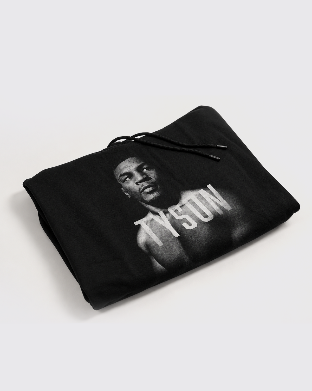 Black hoodie with a black and white portrait of Mike. His body is turned slightly to the left, his face is forward and his eyes are looking off to the right. Slightly transparent white text saying Tyson is featured across his upper chest.