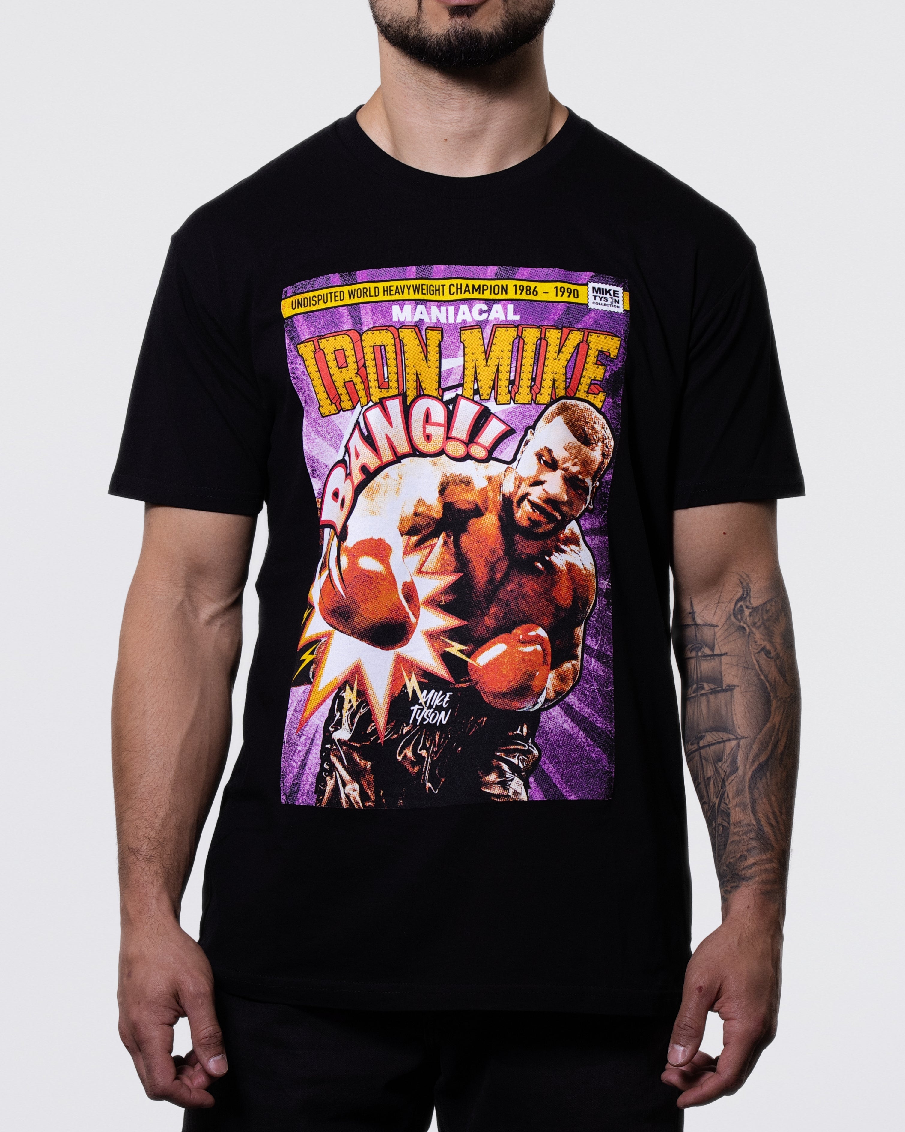 Black T-shirt with a purple comic-style graphic. Text above says "Undisputed World Heavyweight Champion 1986-1990. Maniacal Iron Mike." The center features Mike throwing a punch with the word "Bang" above.