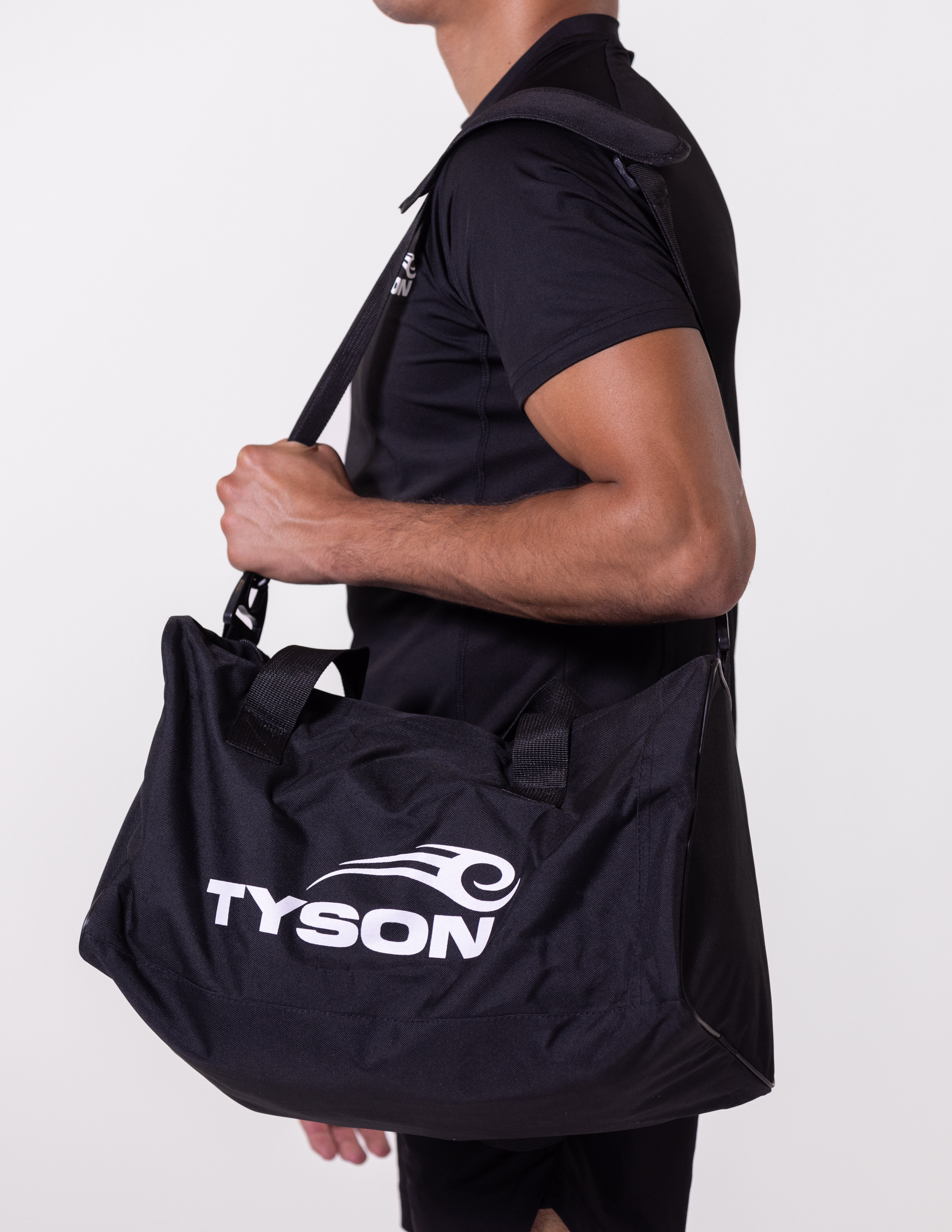 Black rectangular gym bag. The outer face has the white Tyson Pro logo on the bottom right and a mesh pocket to the left. The bag has a shoulder strap and handles.