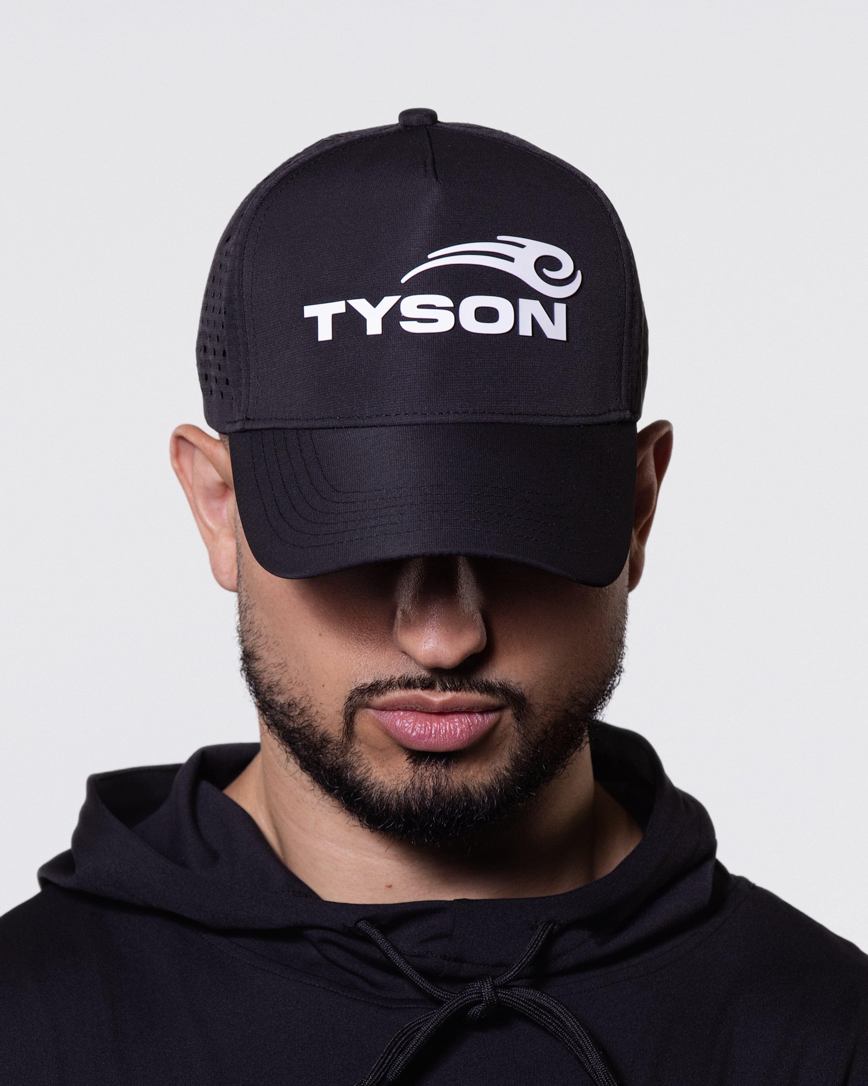 Black baseball-style hat featuring the Tyson Pro logo in white on the front panel. The backside of the hat is mesh and has a snap closure. 